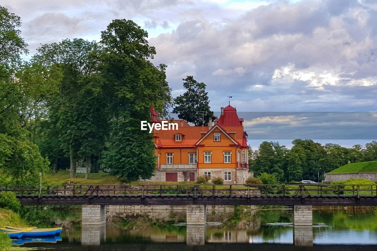 TREES BY RIVER AGAINST BUILDING