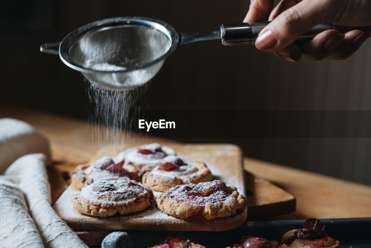 Cropped hand sprinkling powdered sugar on food