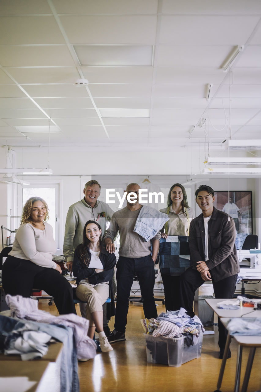 Portrait of smiling fashion designer and colleagues standing together at workshop