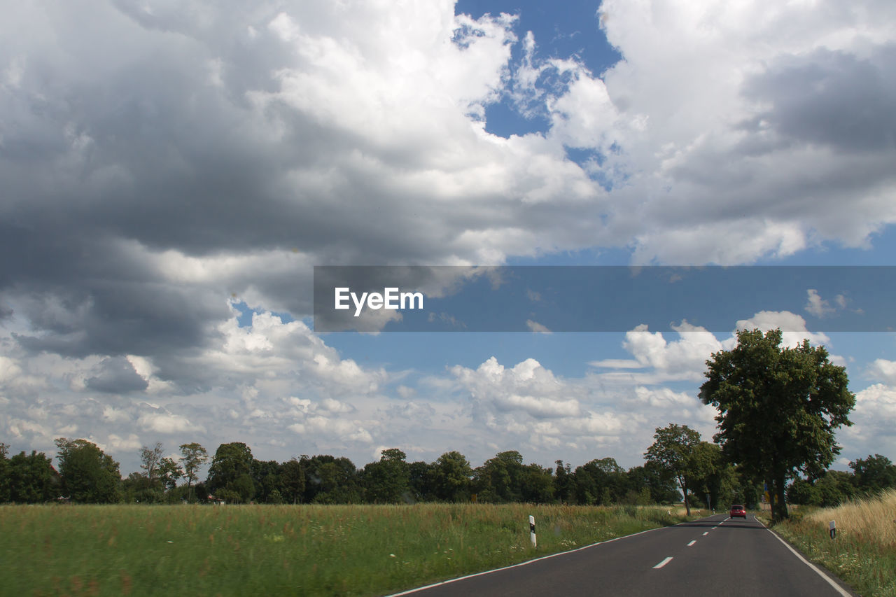 Road by trees against sky