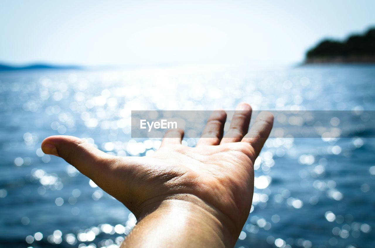 hand, water, nature, sky, sea, one person, close-up, adult, sunlight, blue, wave, finger, relaxation, outdoors, focus on foreground, ocean, day, copy space, holiday, limb, leisure activity, human limb, men, motion, summer, lifestyles
