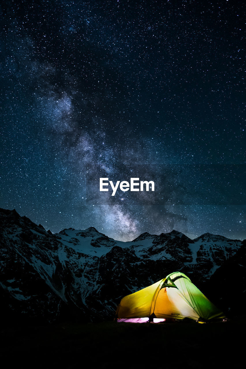 Tent against mountain range at night