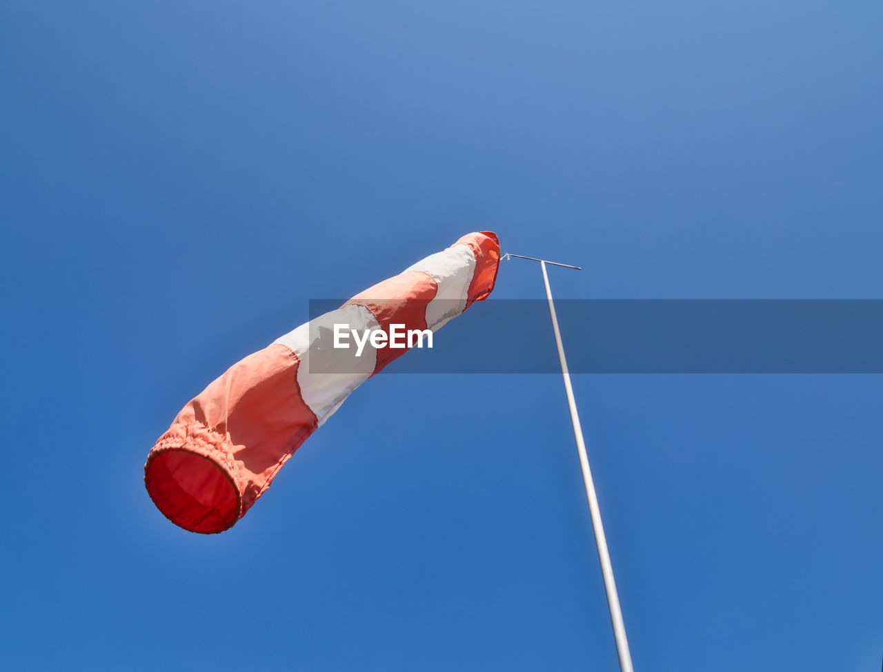 Low angle view of windsock against clear blue sky