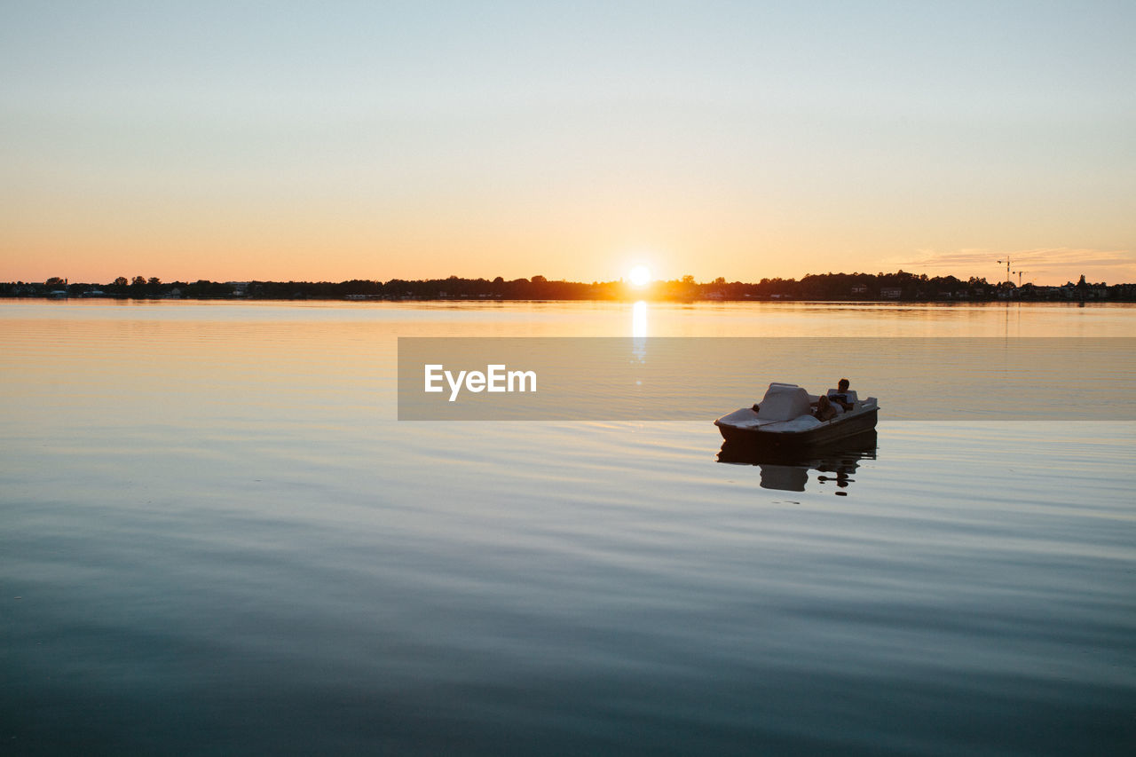 Lake jamno, poland - boy on pedal boat on lake at sunset