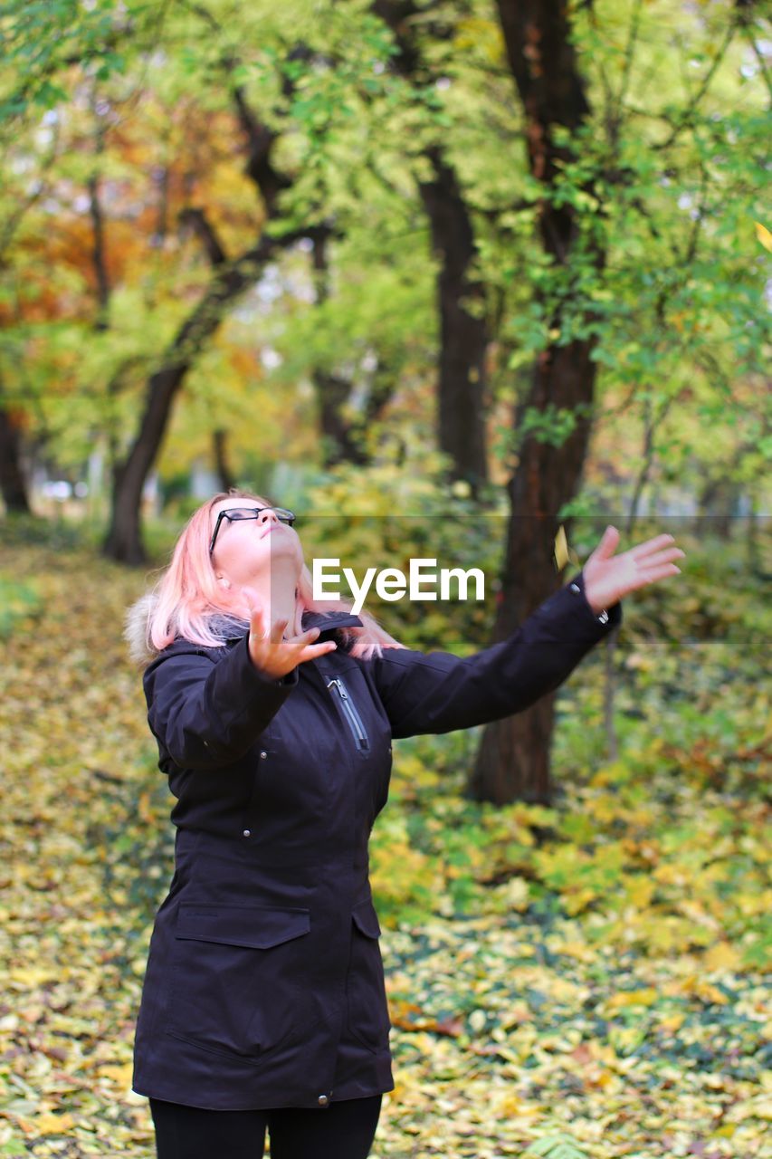 Woman throwing leaves while standing outdoors