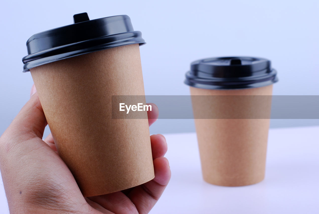 Close-up of hand holding drink against white background