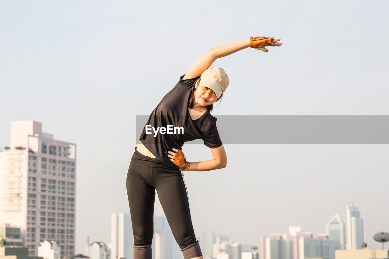 Woman exercising against sky