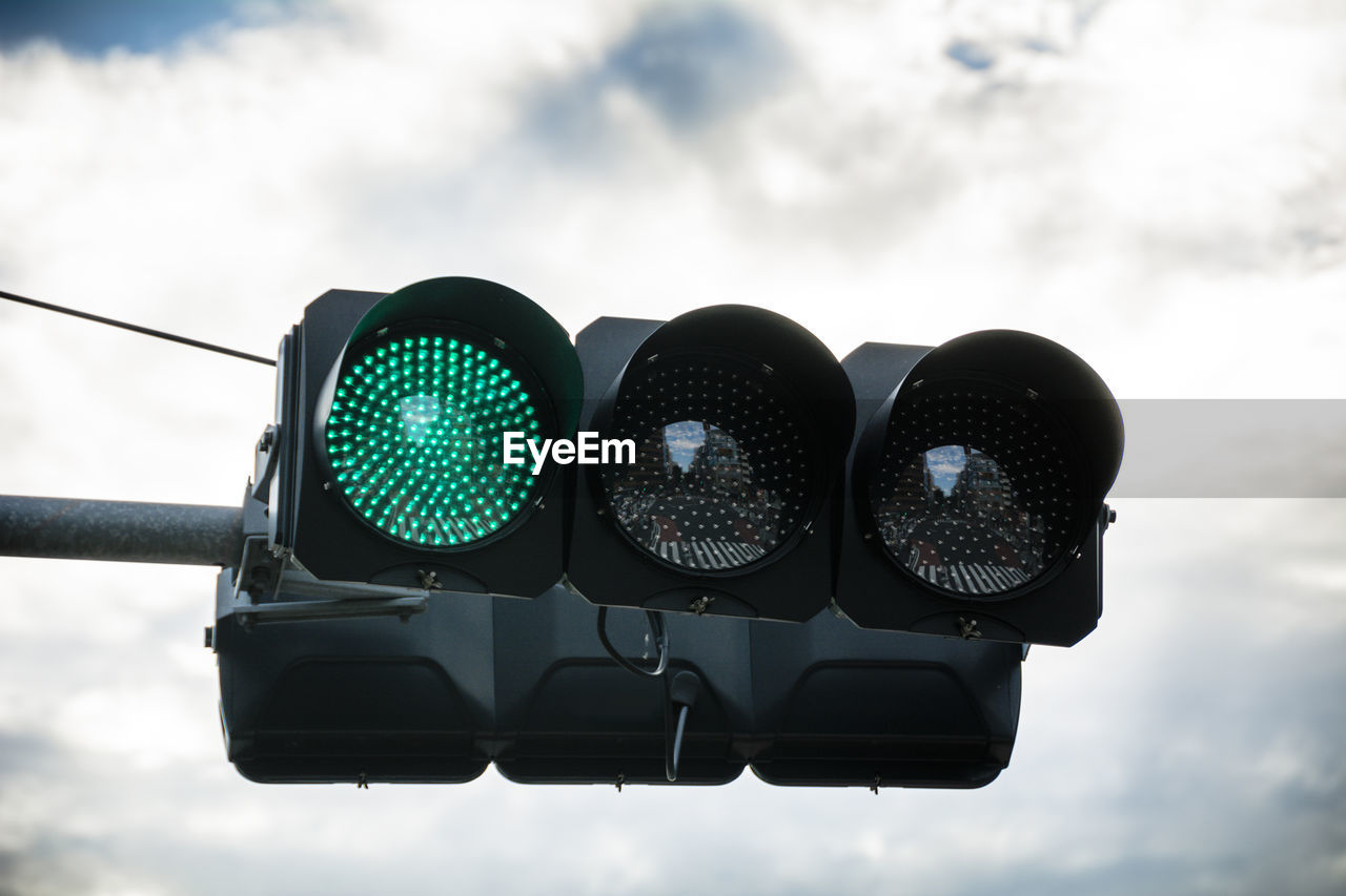 Low angle view of road signal against cloudy sky