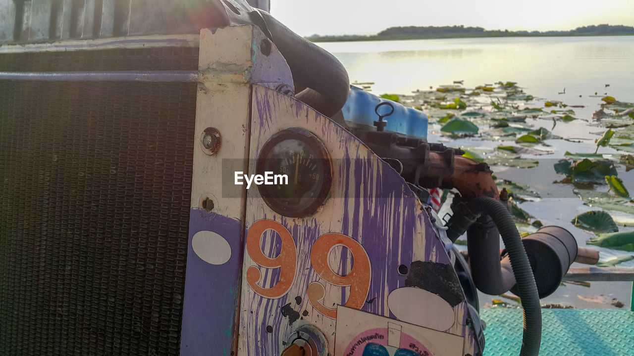 REAR VIEW OF MAN SITTING ON BOAT AGAINST SKY