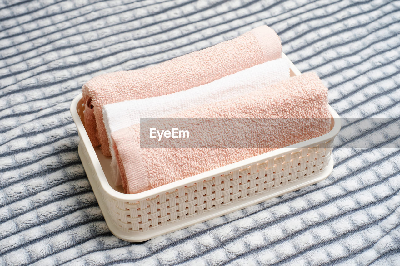 Plastic container with folded towels on a gray background, organizing space.