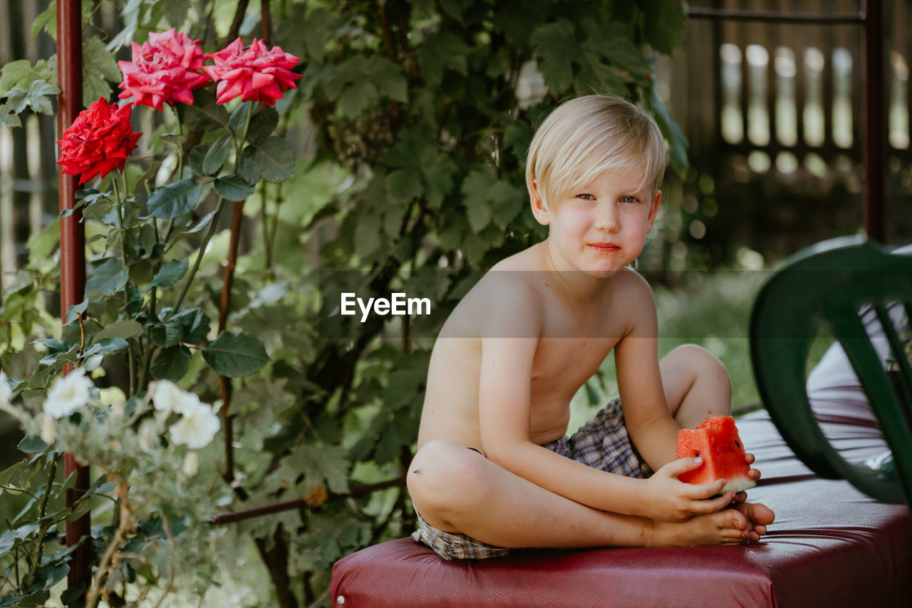 Portrait of shirtless boy sitting outdoors