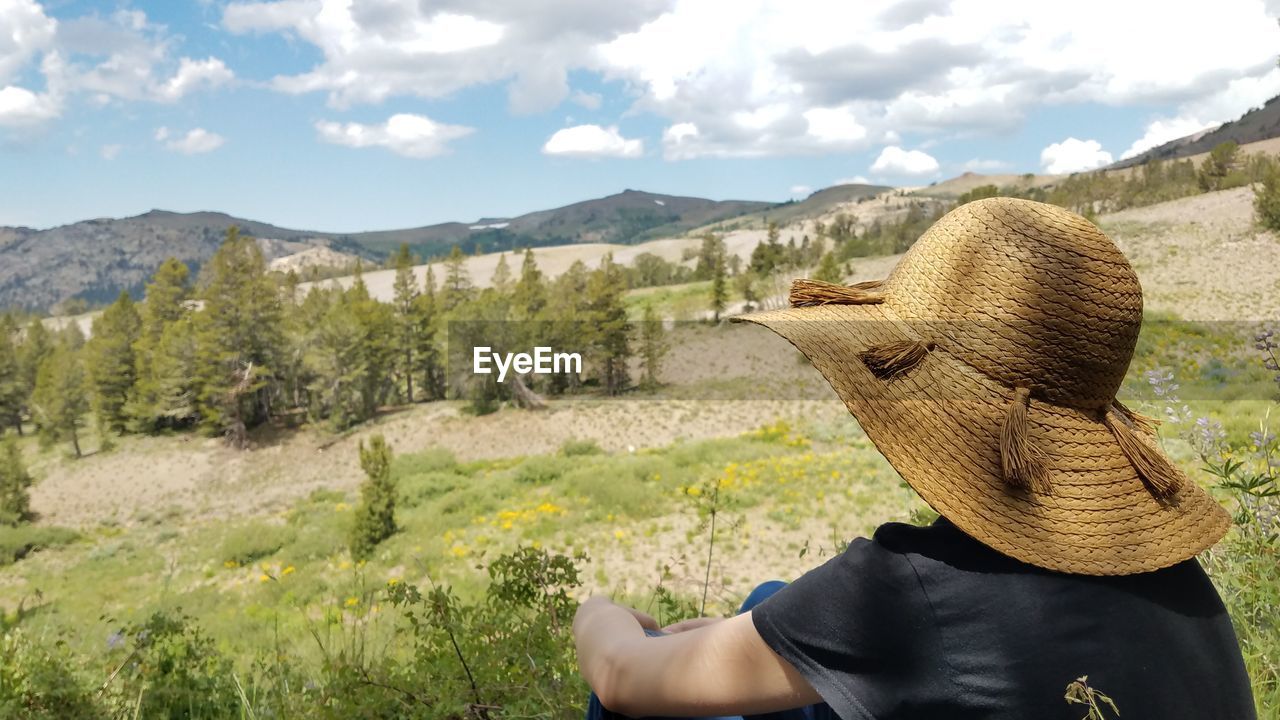 Woman wearing sun hat gazing out at mountains and nature
