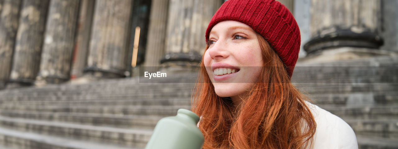 portrait of young woman wearing hat while standing outdoors