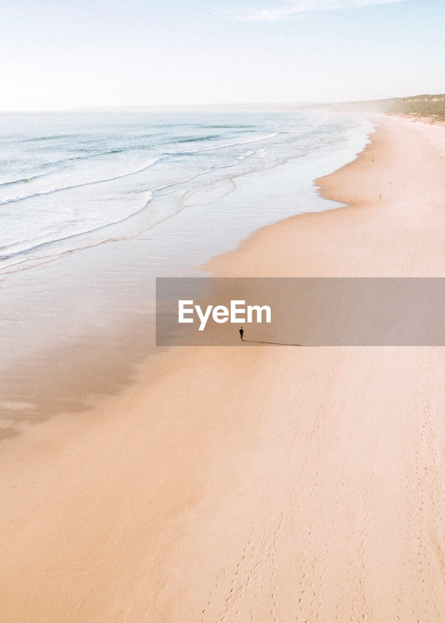 Distant view of person standing at beach against sky