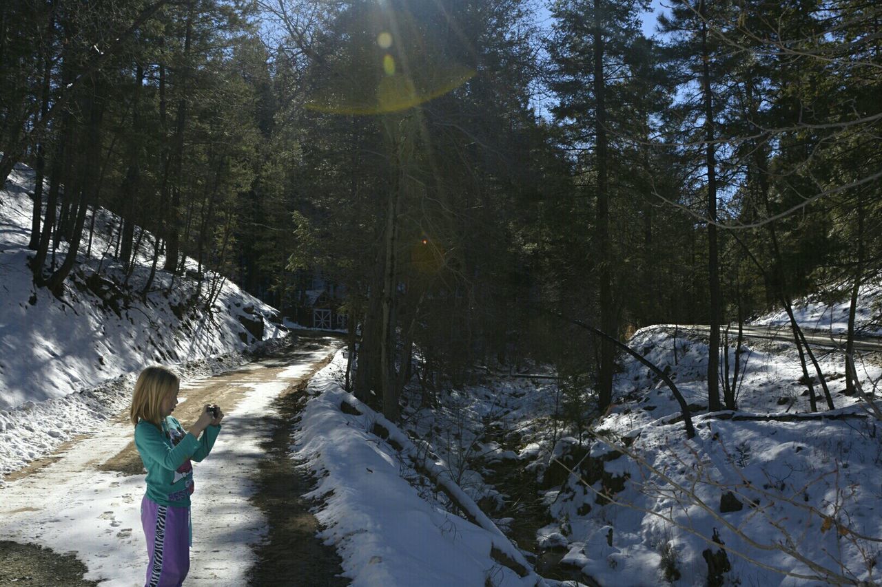 Cute girl photographing snow covered forest