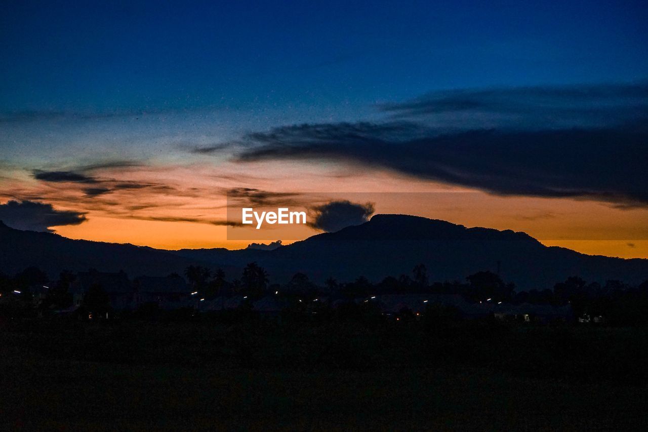 SILHOUETTE LANDSCAPE AGAINST DRAMATIC SKY DURING SUNSET