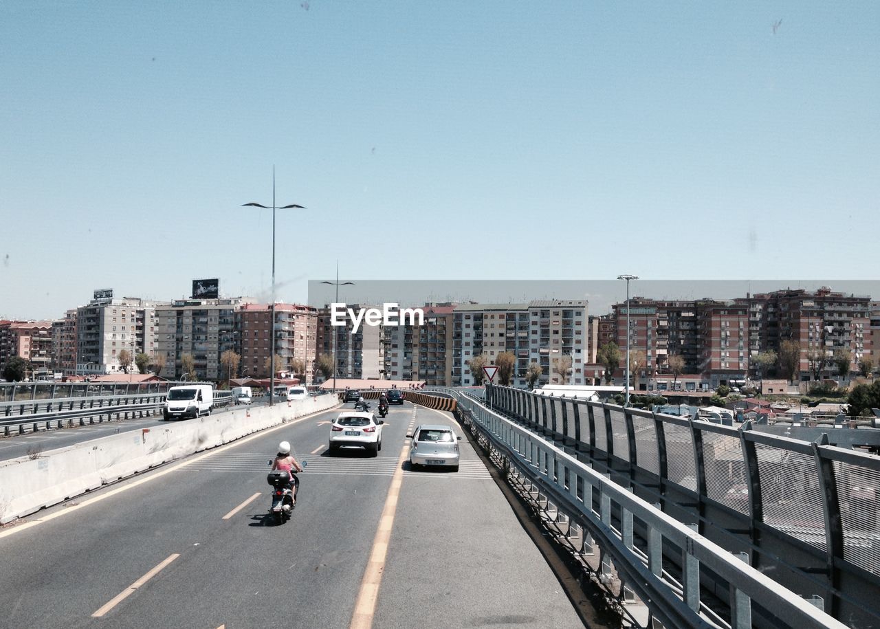 Vehicles on road against clear sky in city