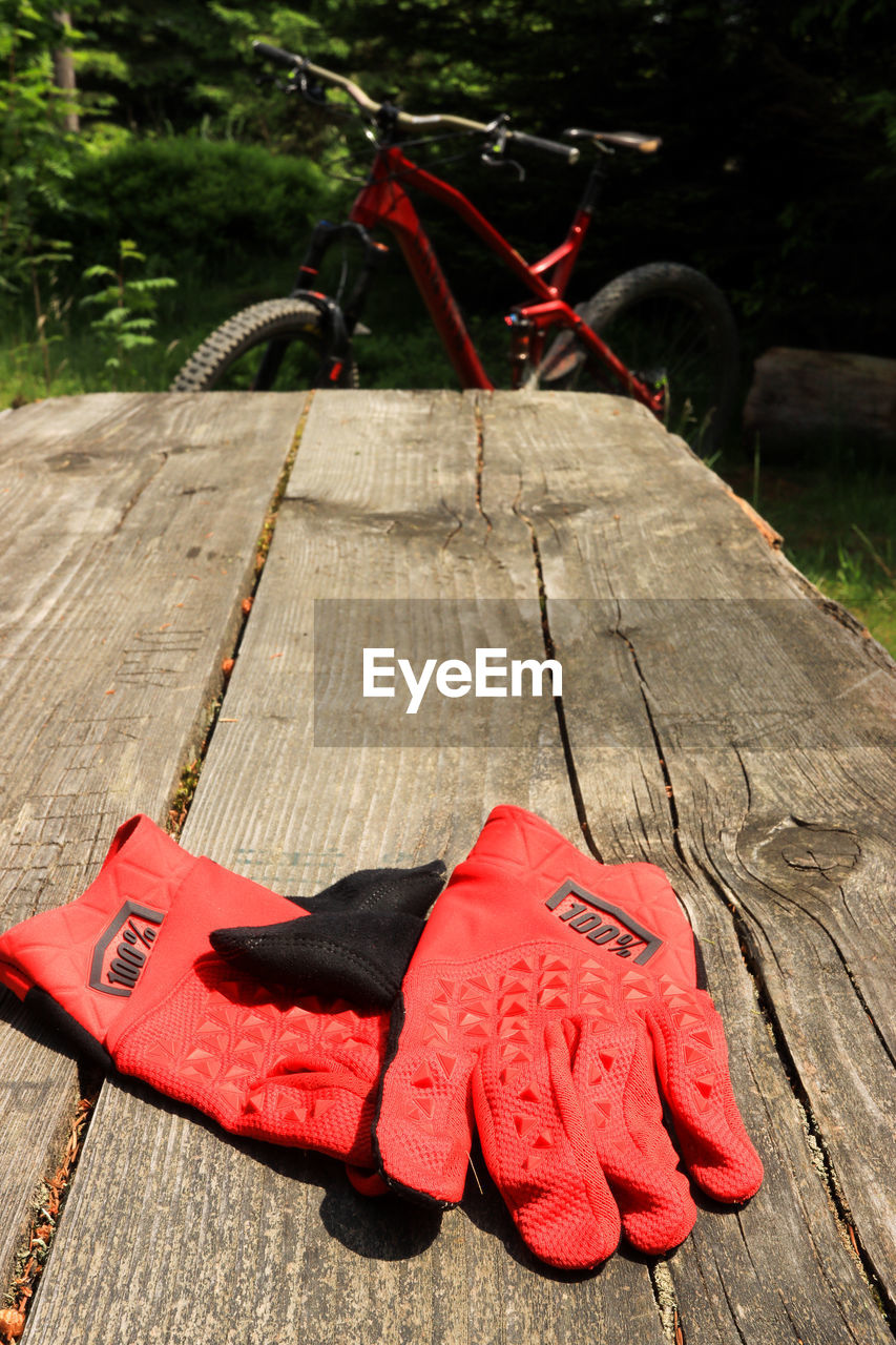 HIGH ANGLE VIEW OF RED BICYCLE ON WOODEN TABLE
