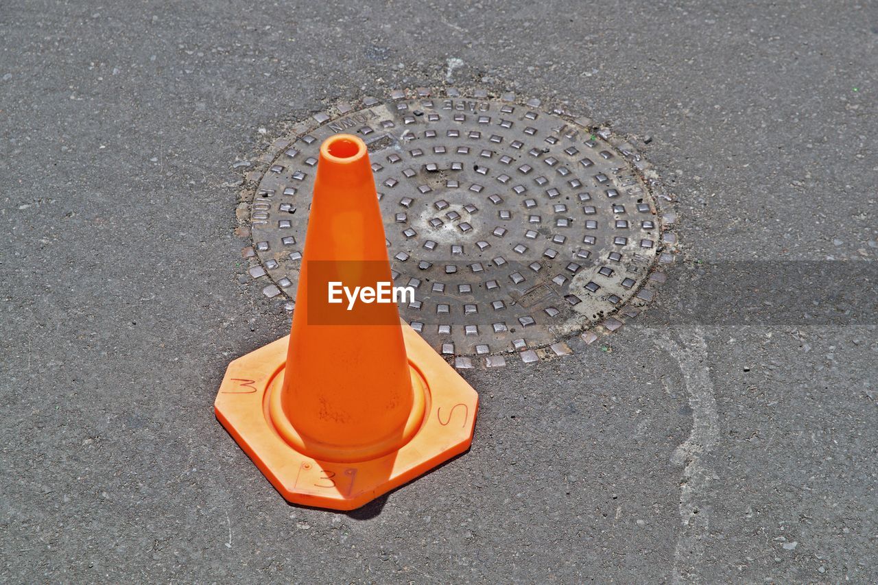 HIGH ANGLE VIEW OF ORANGE UMBRELLA ON STREET