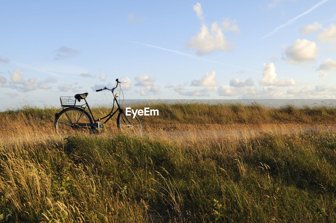 Bicycle on grassy field against sky