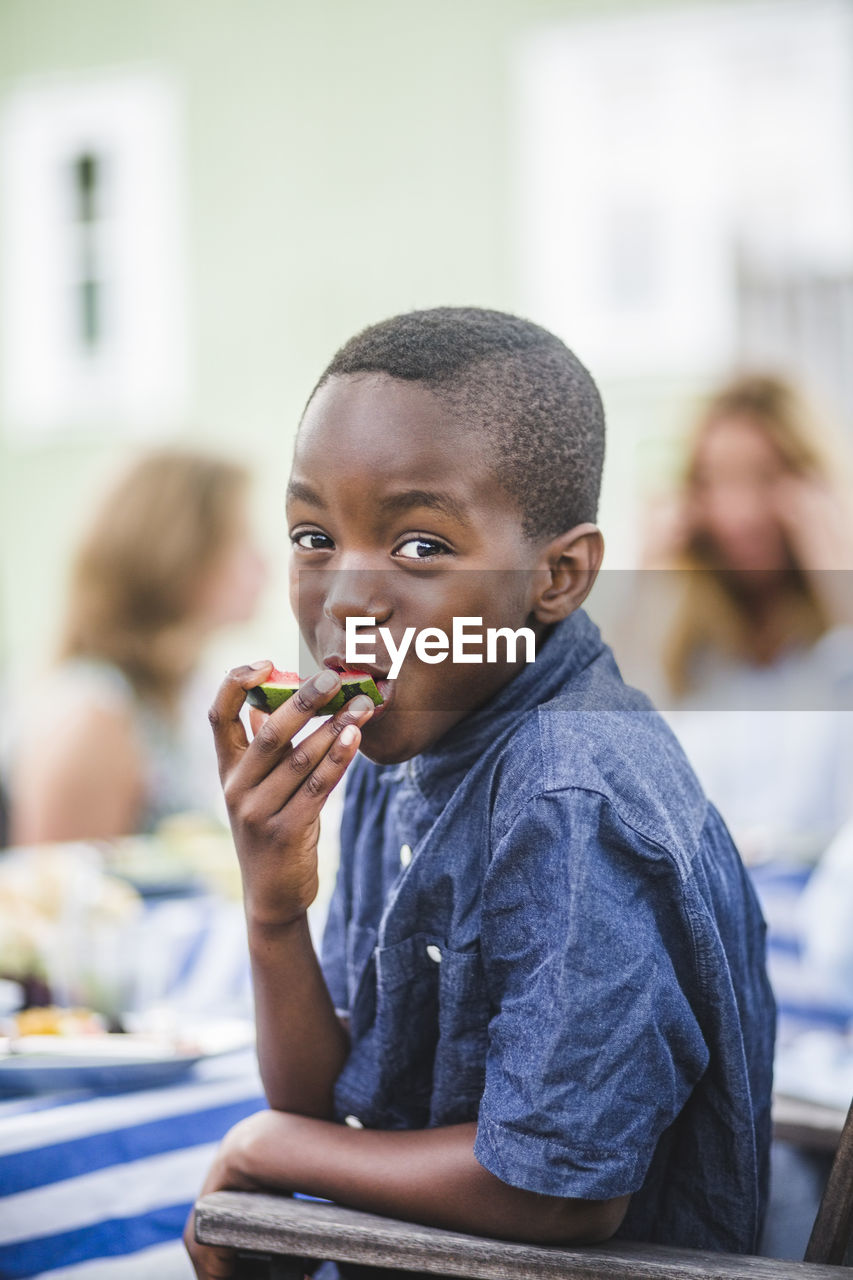 Portrait of smiling boy eating watermelon at party in garden