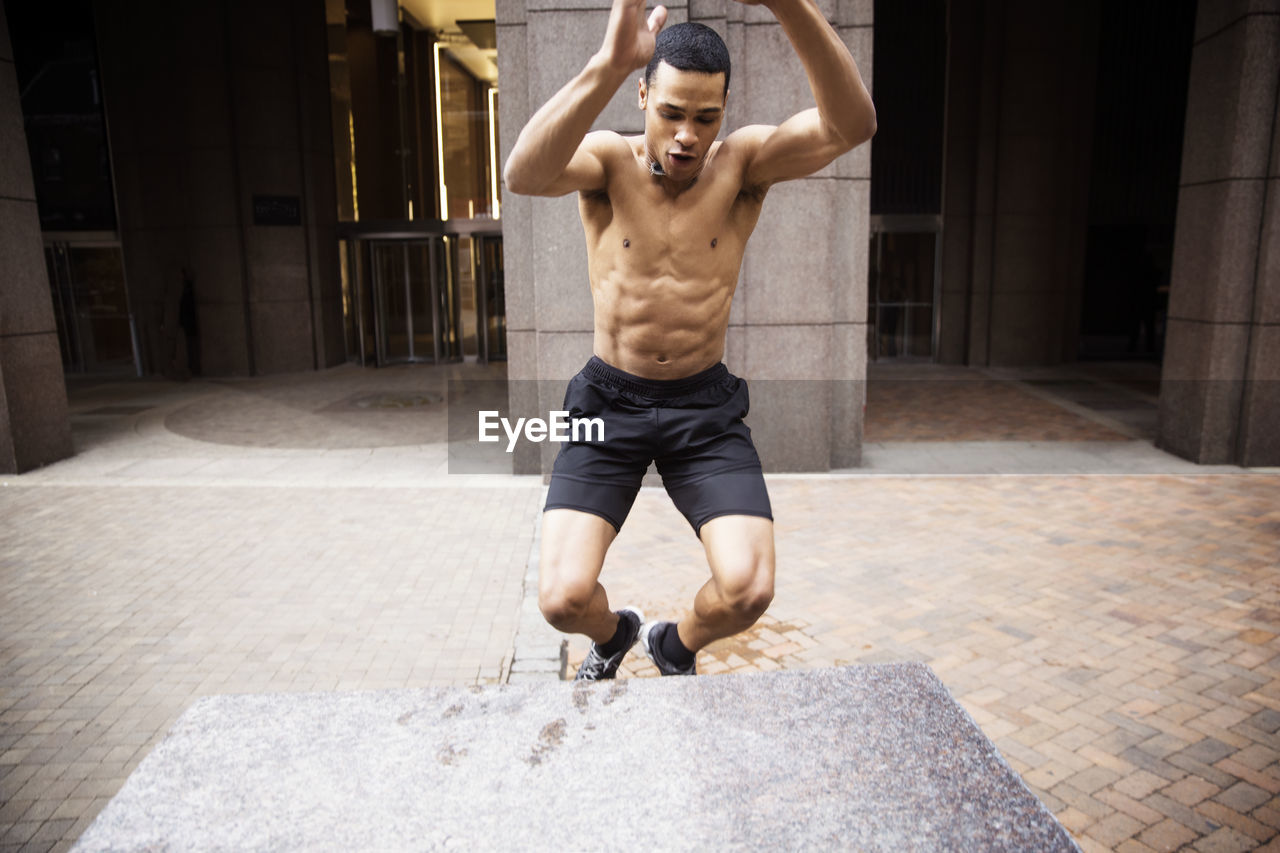 Determined male athlete jumping on footpath