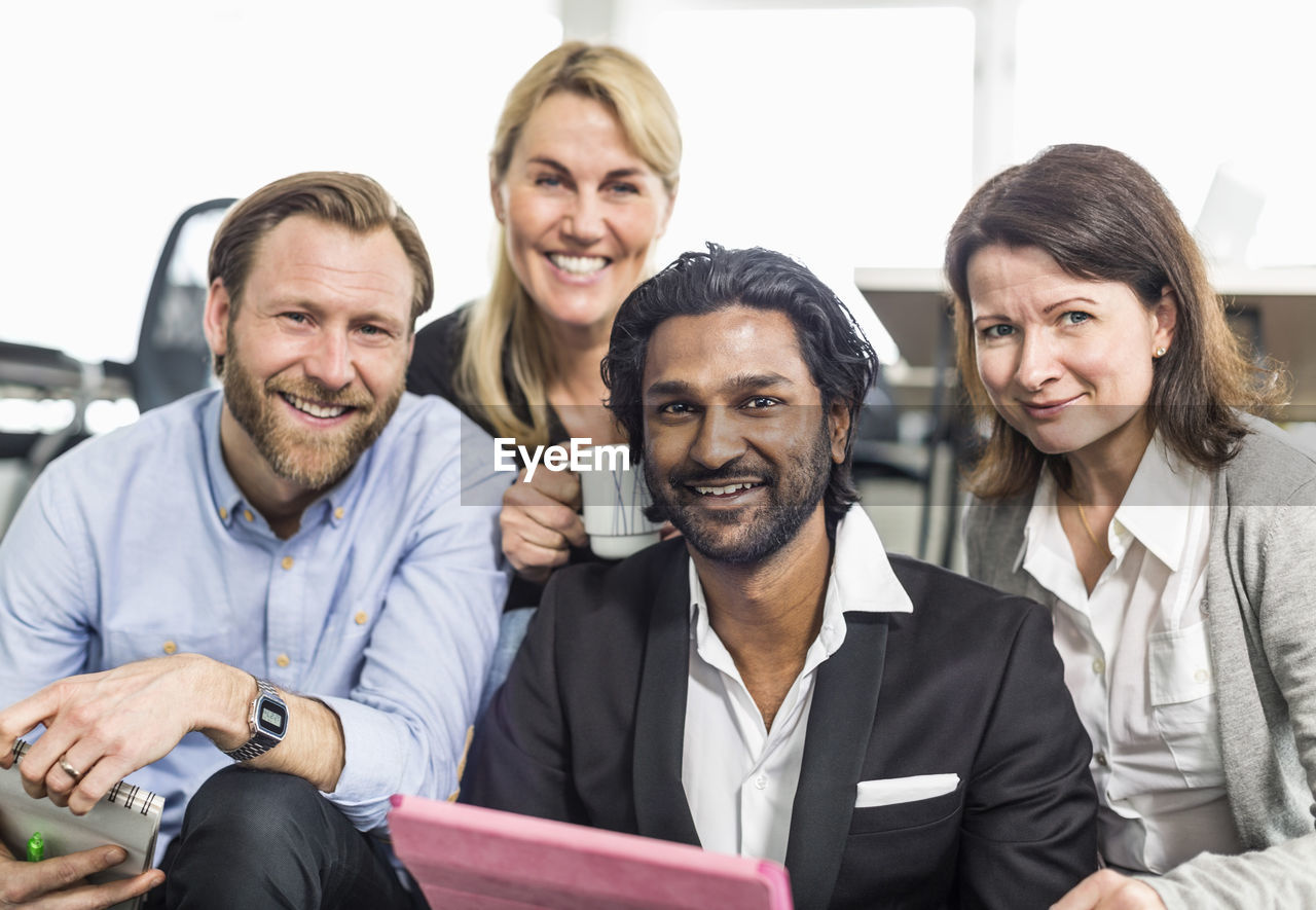 Portrait of happy multi-ethnic business people sitting together in office