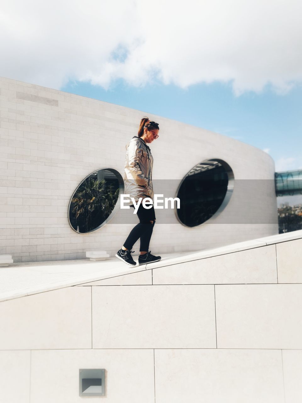 FULL LENGTH OF WOMAN STANDING AGAINST BUILDING