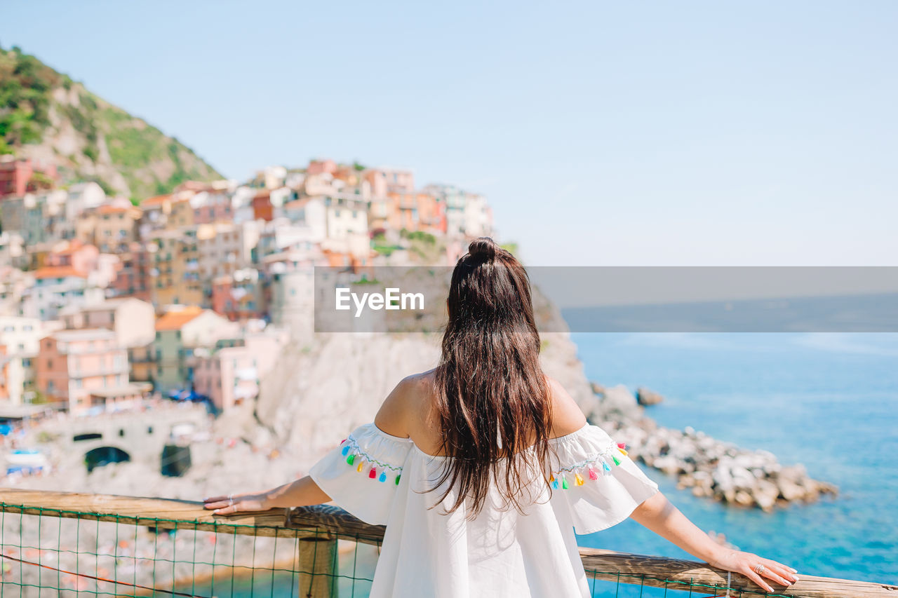 REAR VIEW OF WOMAN LOOKING AT SEA