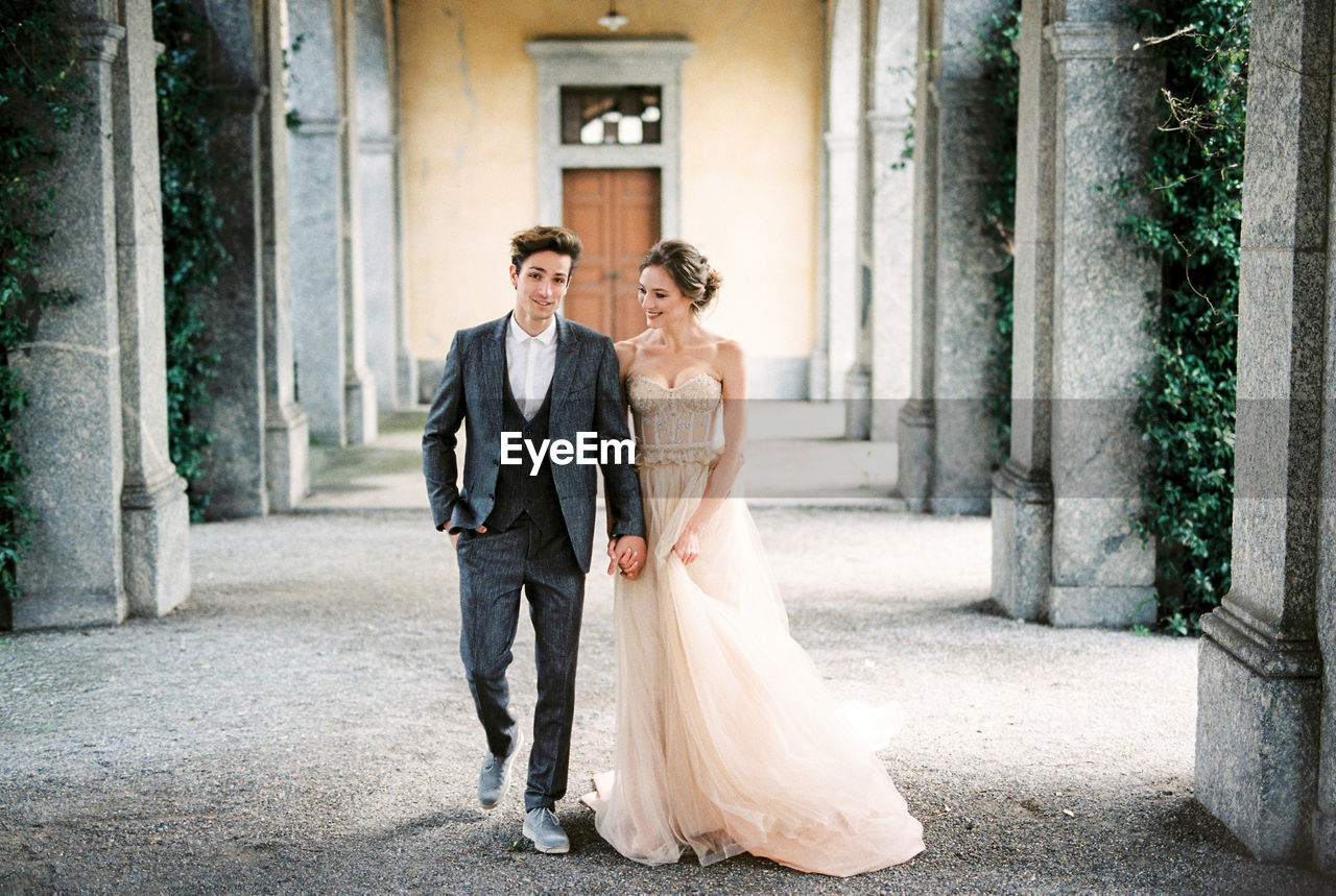 full length of bride and bridegroom standing in city