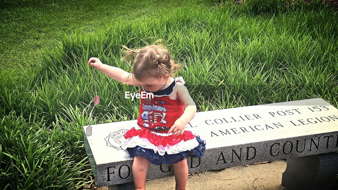 Girl holding dog tag while sitting on bench
