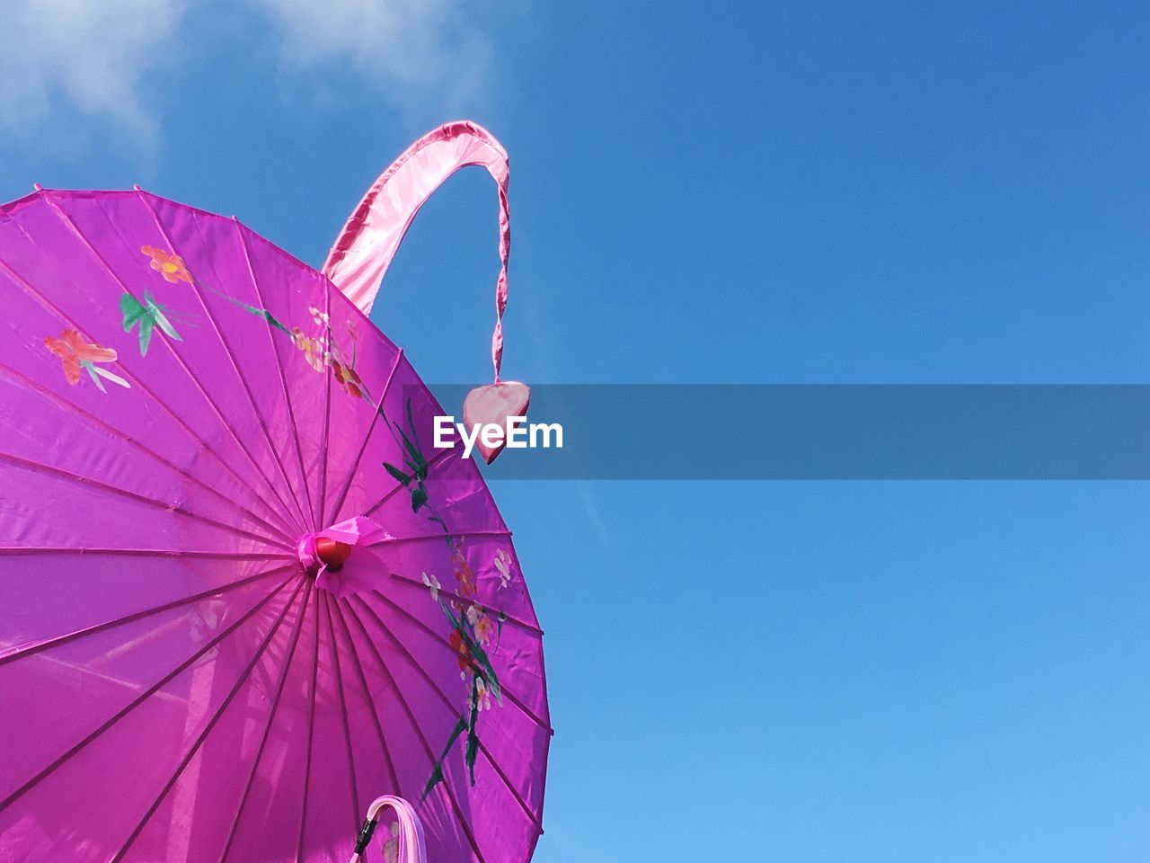 Low angle view of pink parasol against blue sky