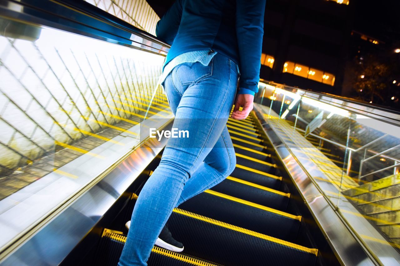 Low section of women walking on escalator