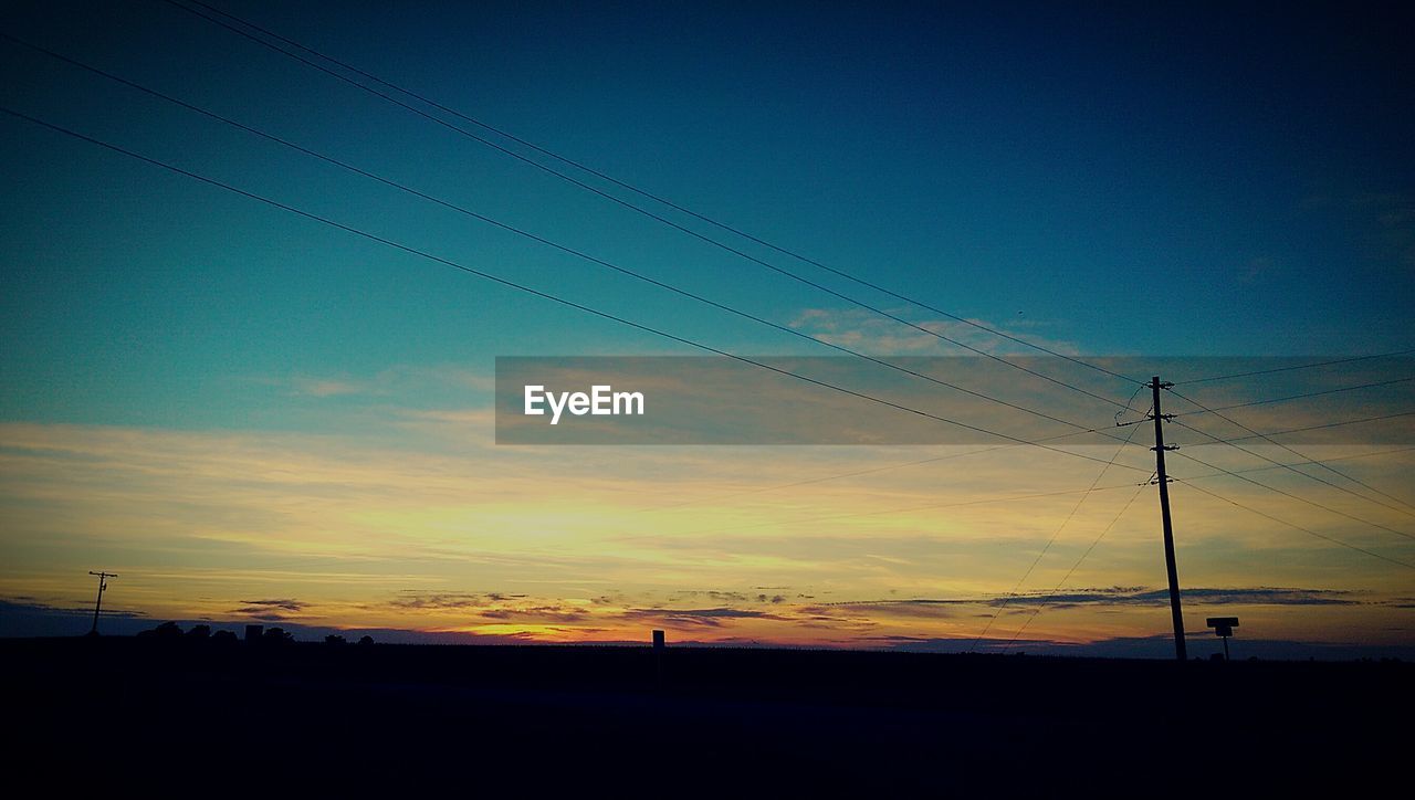 Silhouette electricity pylon against sky during sunset