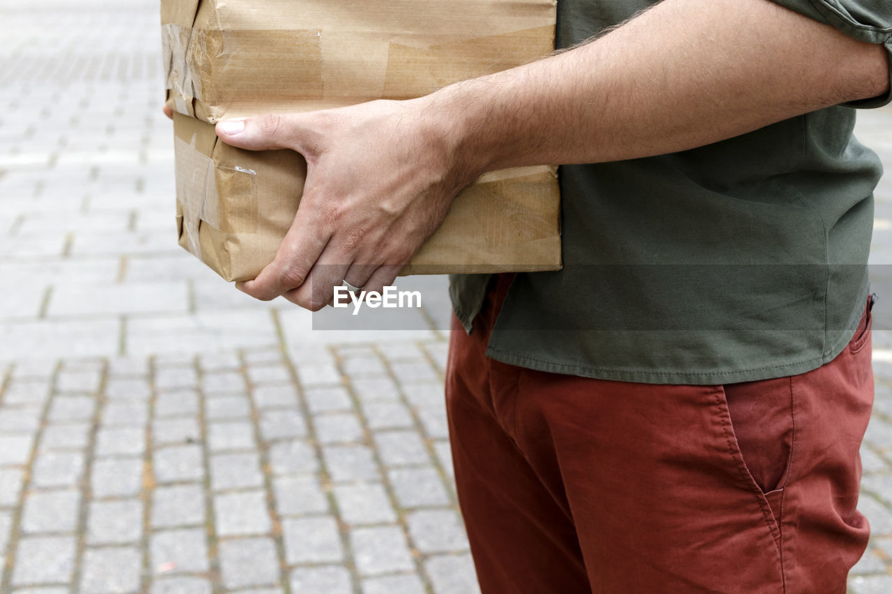 Midsection of man holding boxes on street