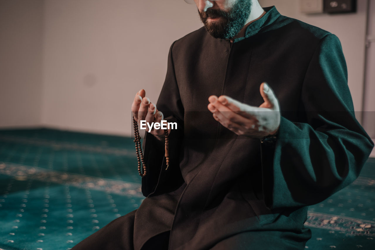 Midsection of man holding sitting in mosque