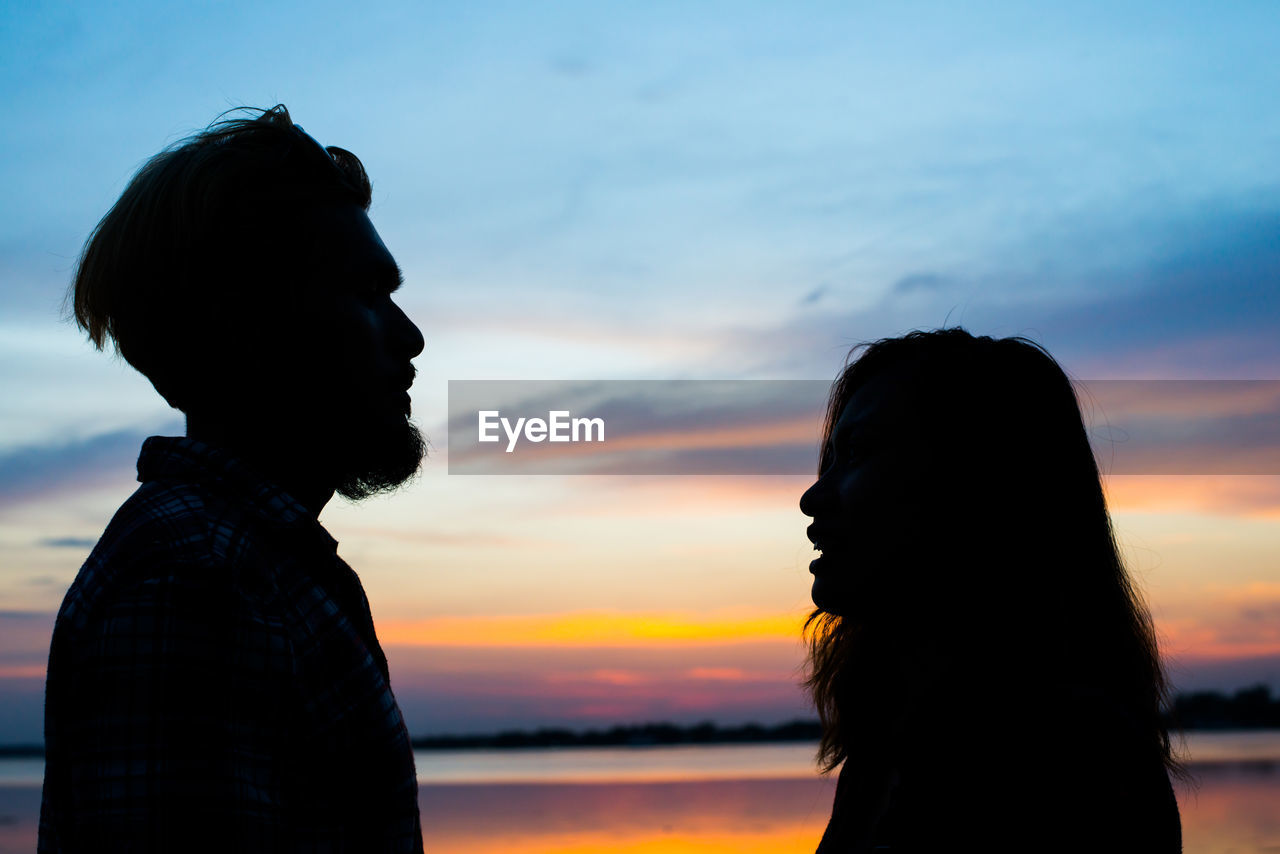 Silhouette man and woman against sky during sunset