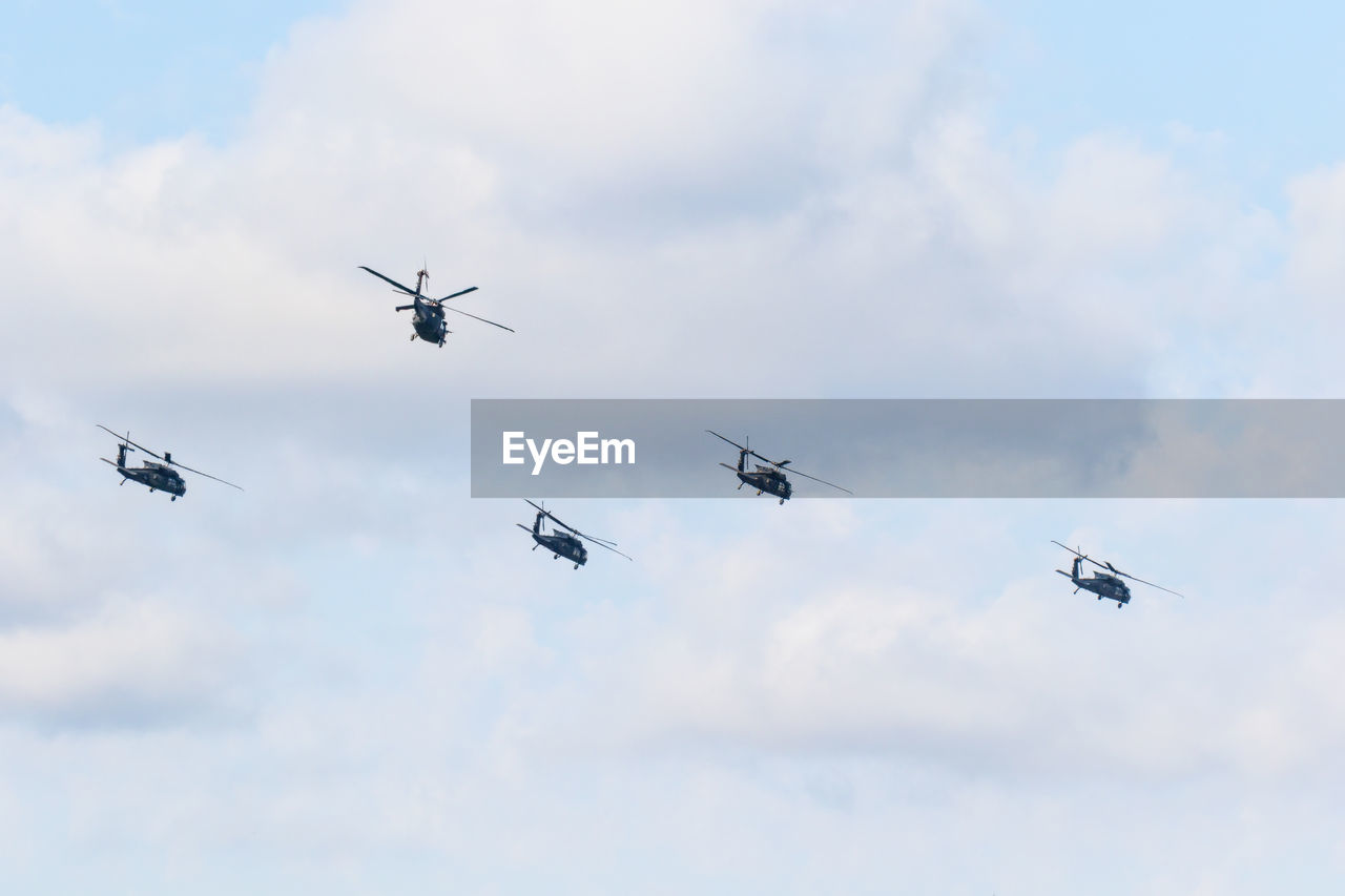 Low angle view of helicopters flying against sky