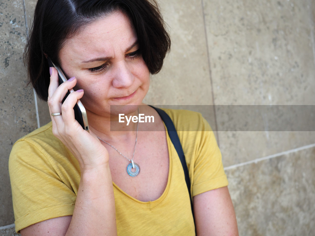 Close-up of mature man talking on mobile phone by wall