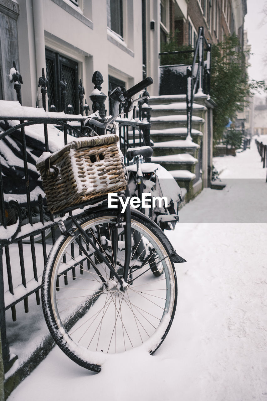 Bicycle on snow covered street against buildings in city