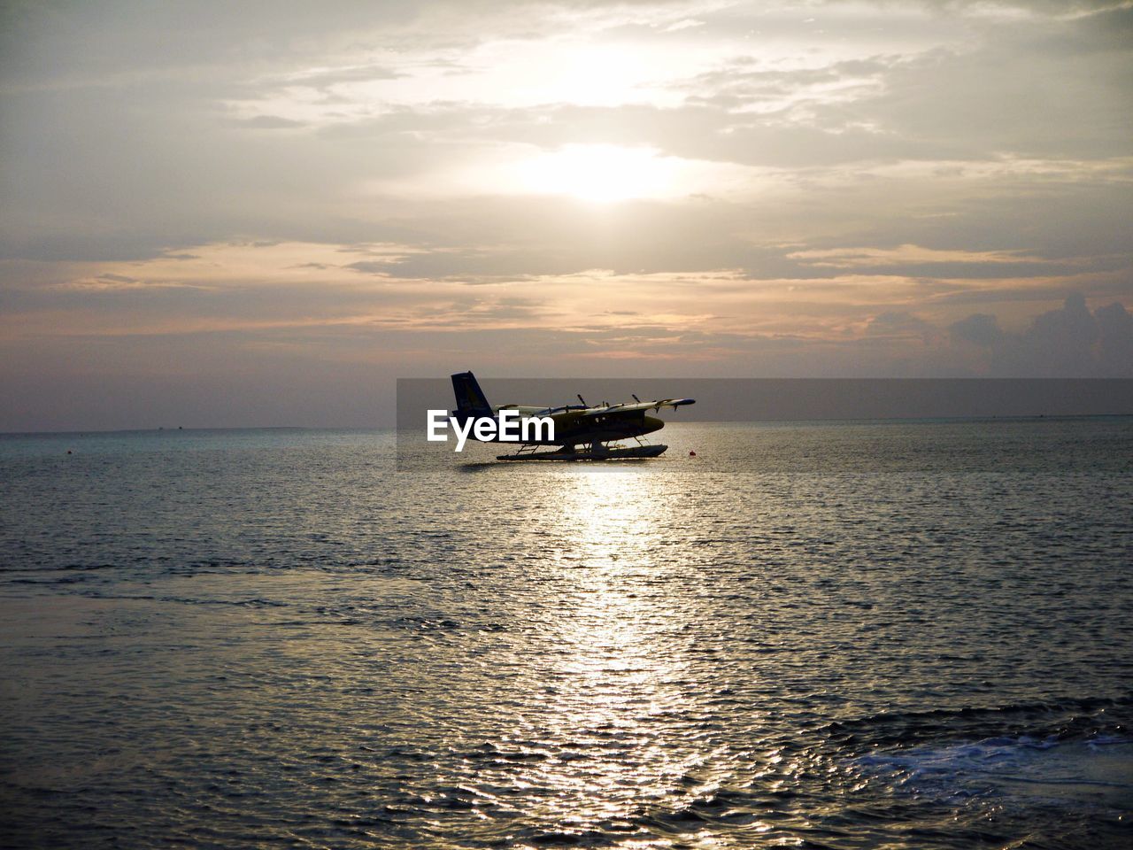 Seaplane on sea against sky during sunset