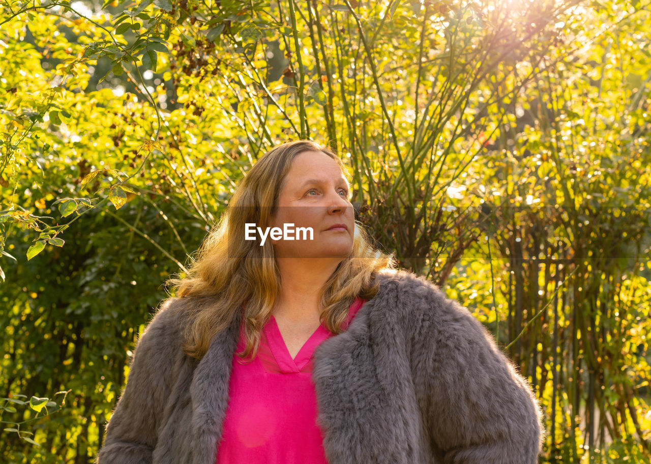 Woman looking up against trees during winter