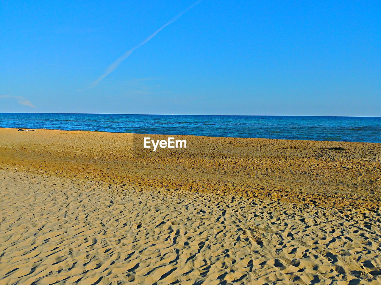 Scenic view of beach against clear blue sky