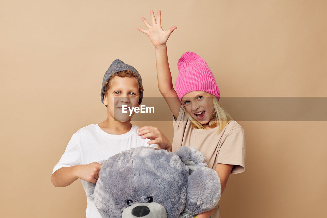 portrait of smiling young woman with stuffed toy against pink background