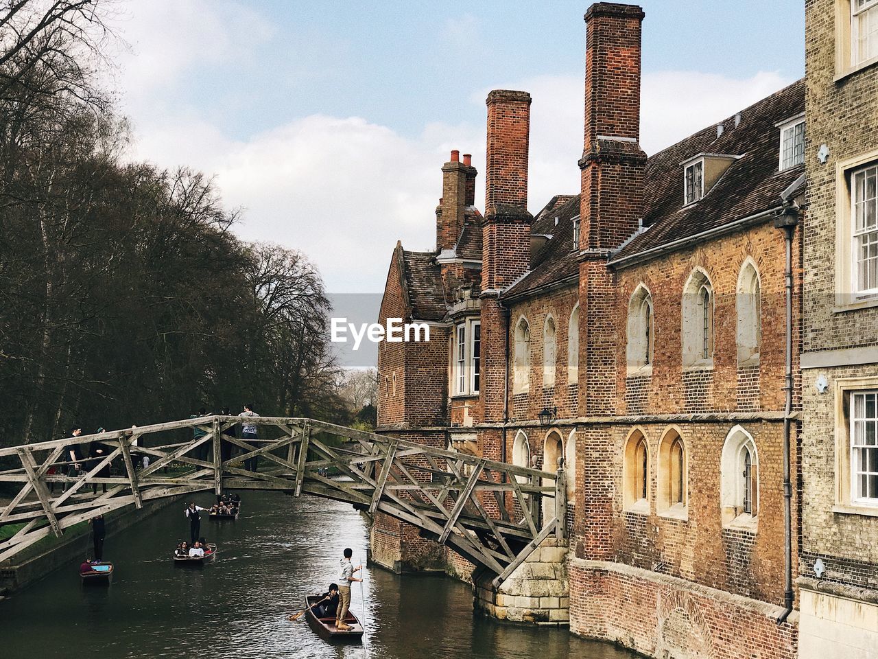 Bridge over canal by buildings against sky