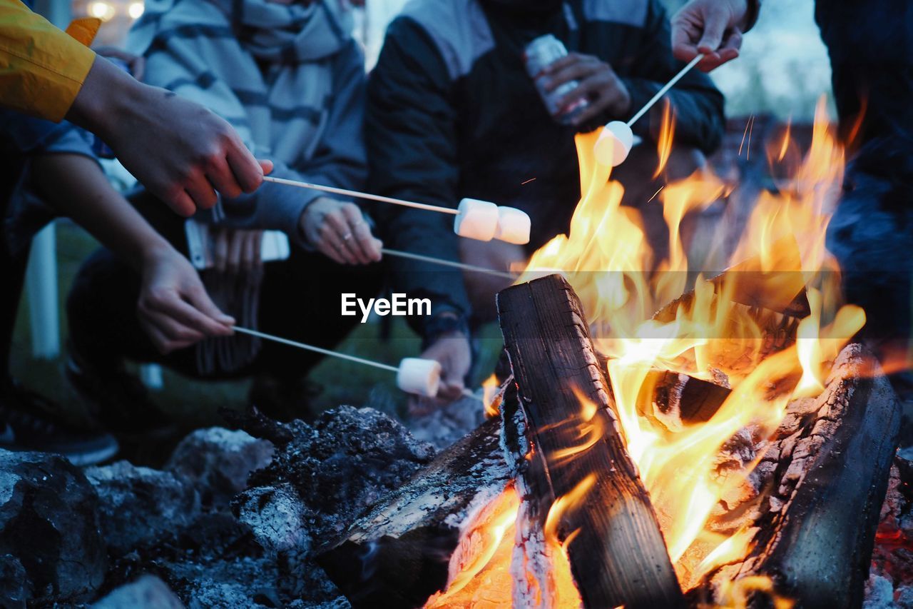 Low section of people having marshmallows on barbecue