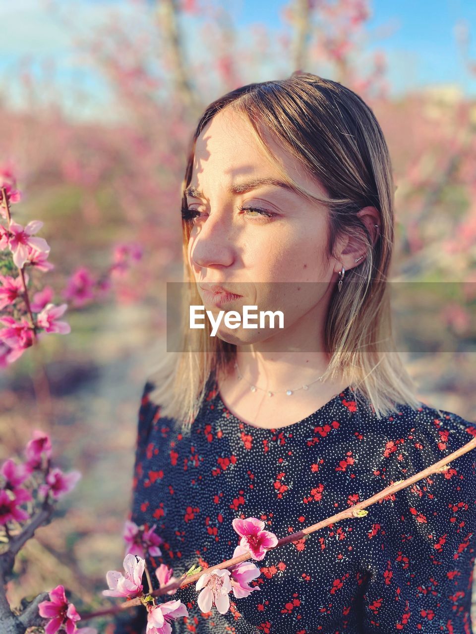 Portrait of woman with pink flowers against blurred background