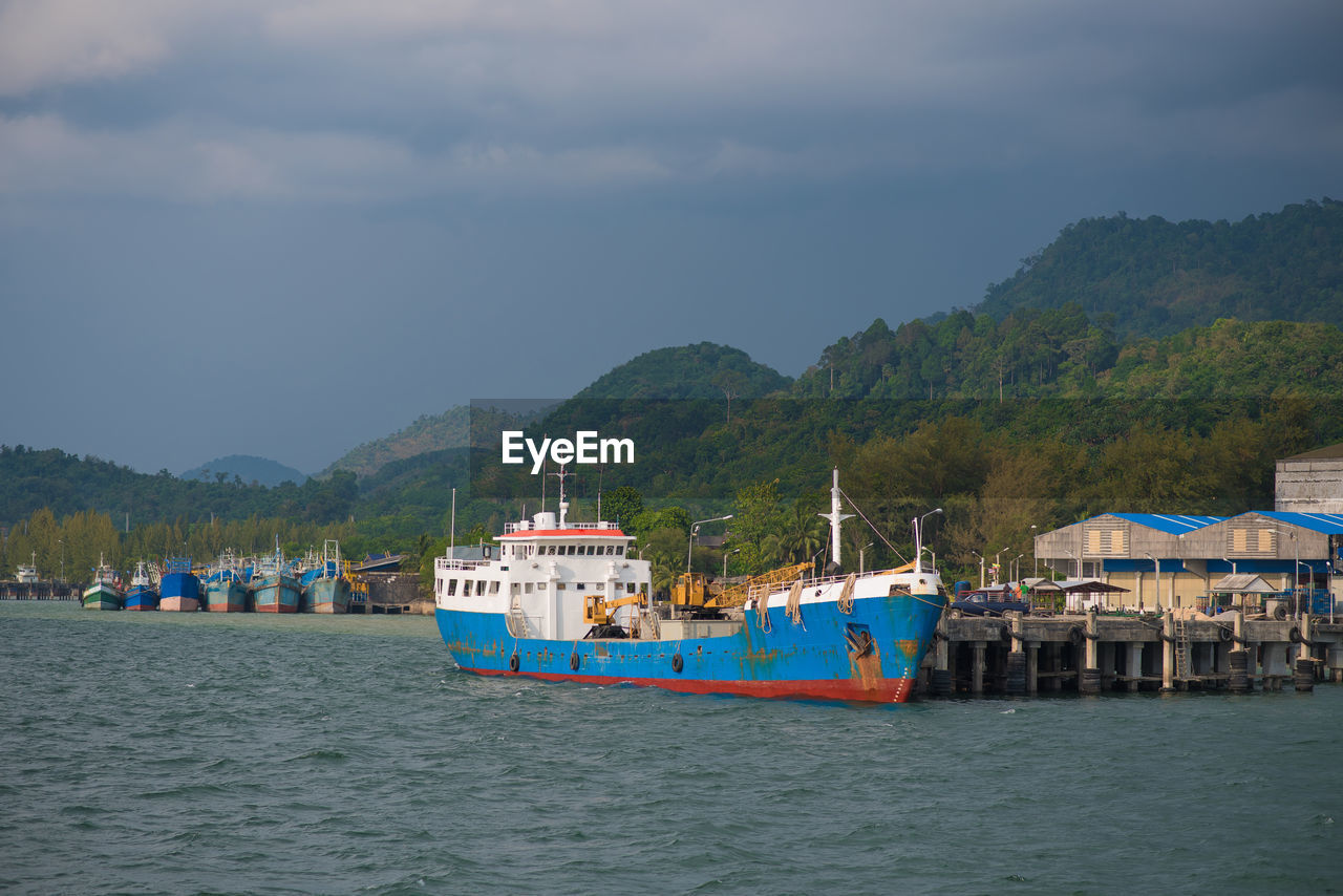 FISHING BOATS IN SEA AGAINST MOUNTAINS