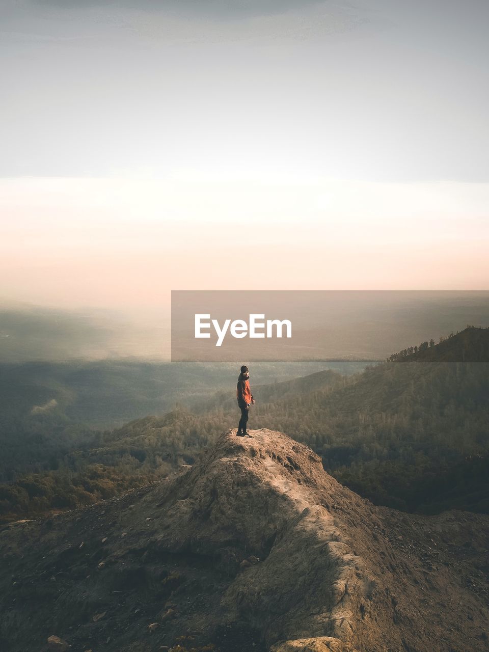 Mid distance view of man standing on cliff against sky