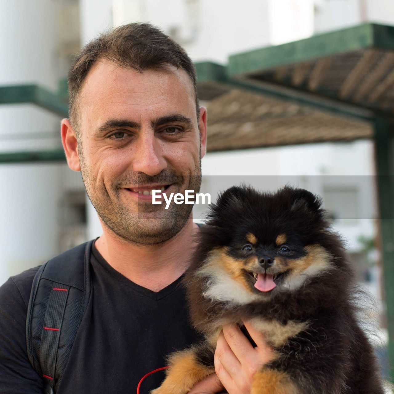 Portrait of smiling man carrying dog in city